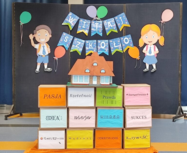 Dekoracja szkolna z napisem „Witaj Szkoło”, postaciami uczniów, balonikami i kolorowymi pudełkami z wartościami: pasja, rzetelność, prawda, zaangażowanie, idea, misja, wiedza, sukces, entuzjazm, mądrość, odkrywanie, kreatywność.