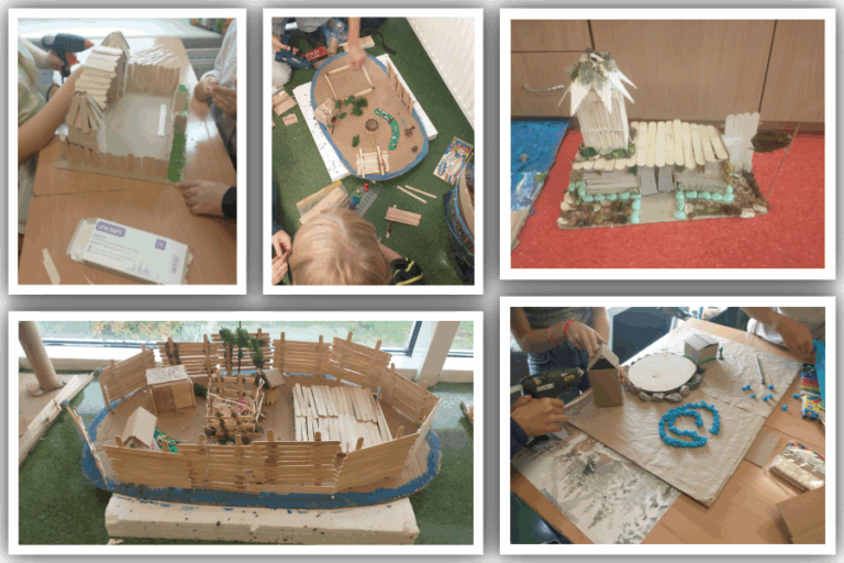 Dzieci tworzą makietę osady z drewnianych patyczków, kartonu i modeliny, budując ogrodzenia, chaty i elementy terenu podczas wspólnej pracy przy stole i na podłodze.