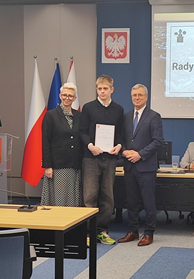 Uczeń pozuje wraz z burmistrzem i sekretarzem gminy