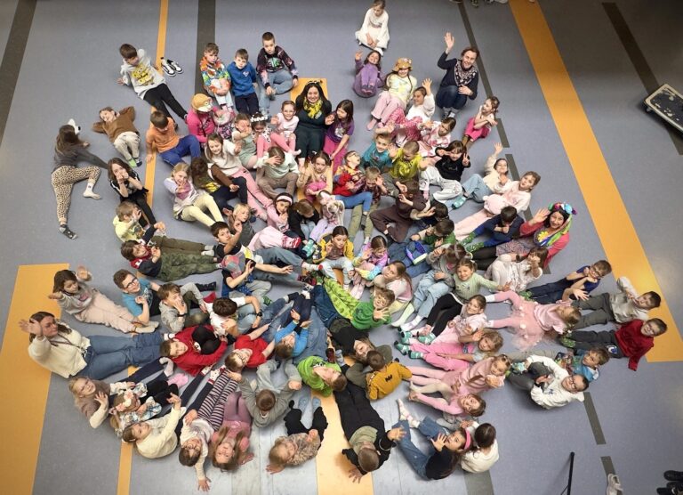 Uczniowie zebrani w holu szkoły prezentujący różnokolorowe skarpetki